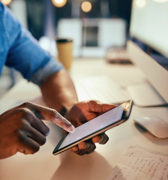 Cropped shot of an unrecognizable businessman using a cellphone while working late in the office